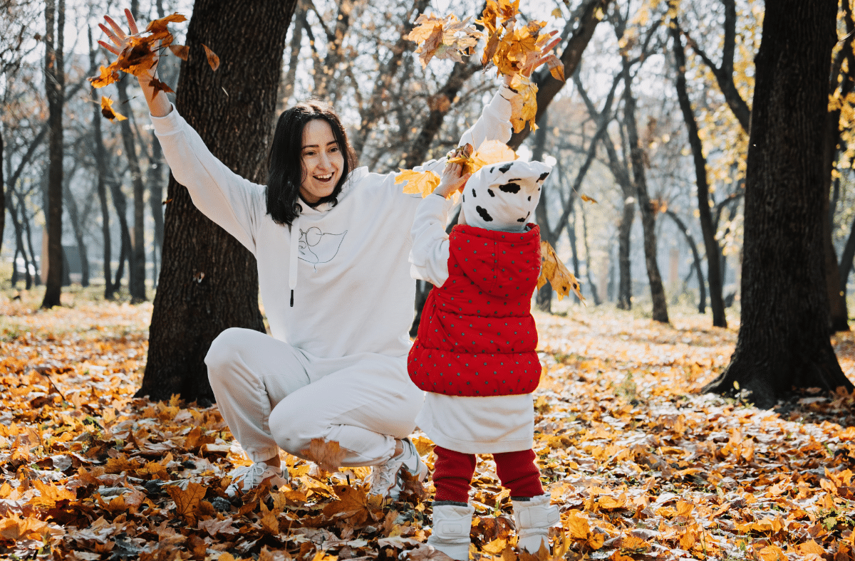 mother and child playing in the fall leaves