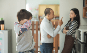 boy covering ears as parents fight