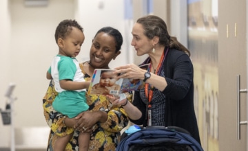 An early childhood professional showing a book to a mother and her toddler