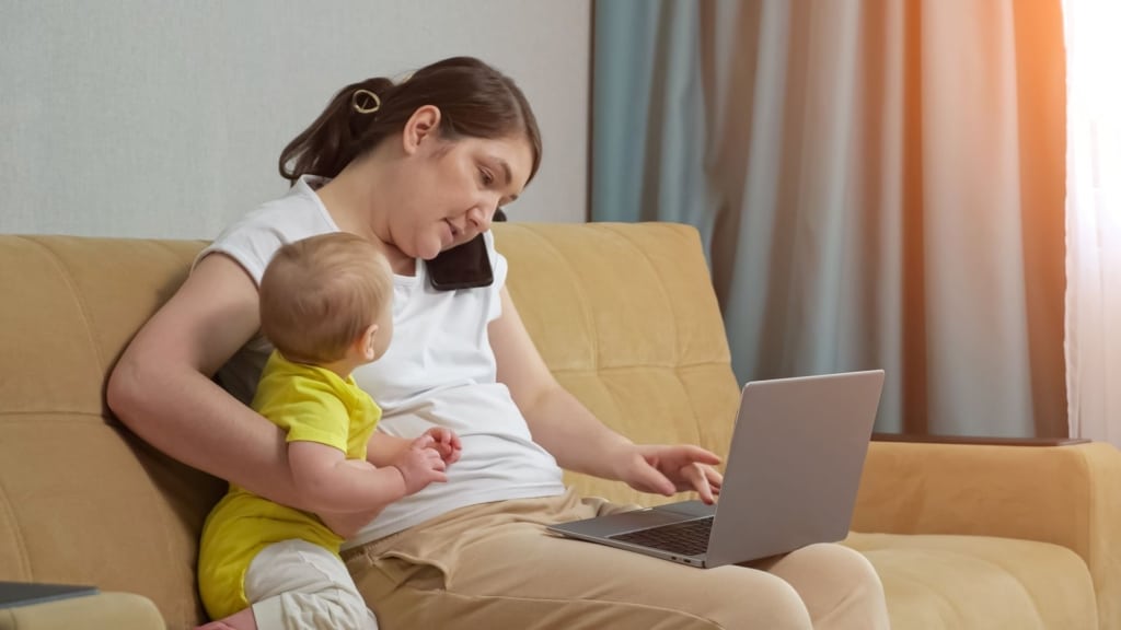 mother on the phone with her infant at her side