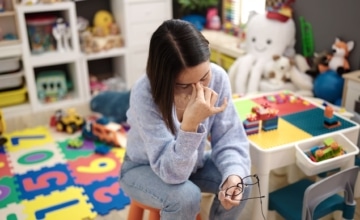 a child care worker holding her head in her hands