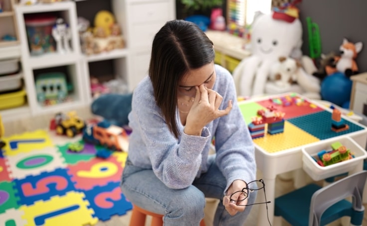 a child care worker holding her head in her hands