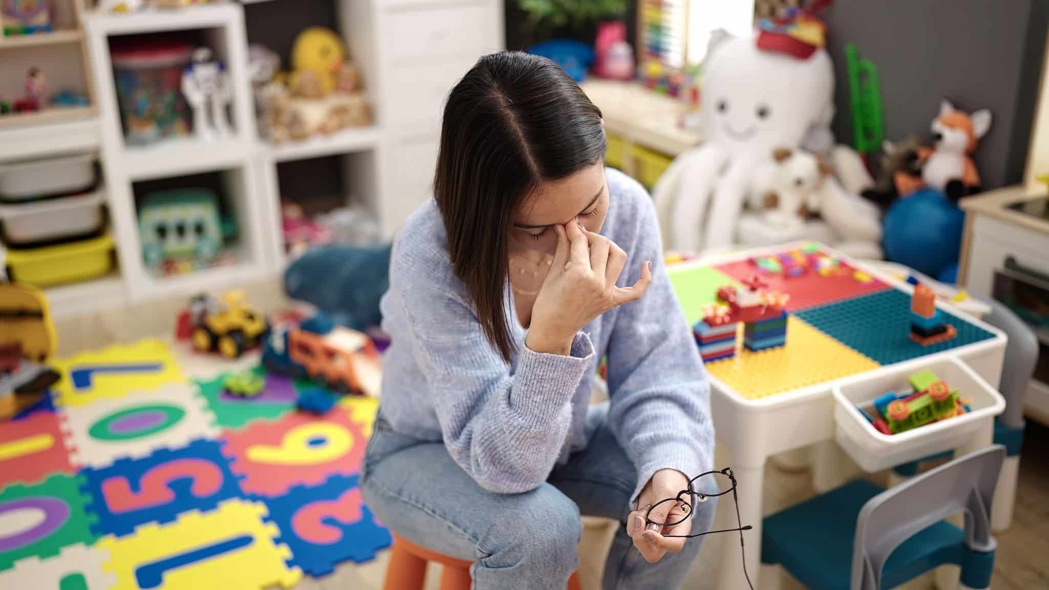 a child care worker holding her head in her hands