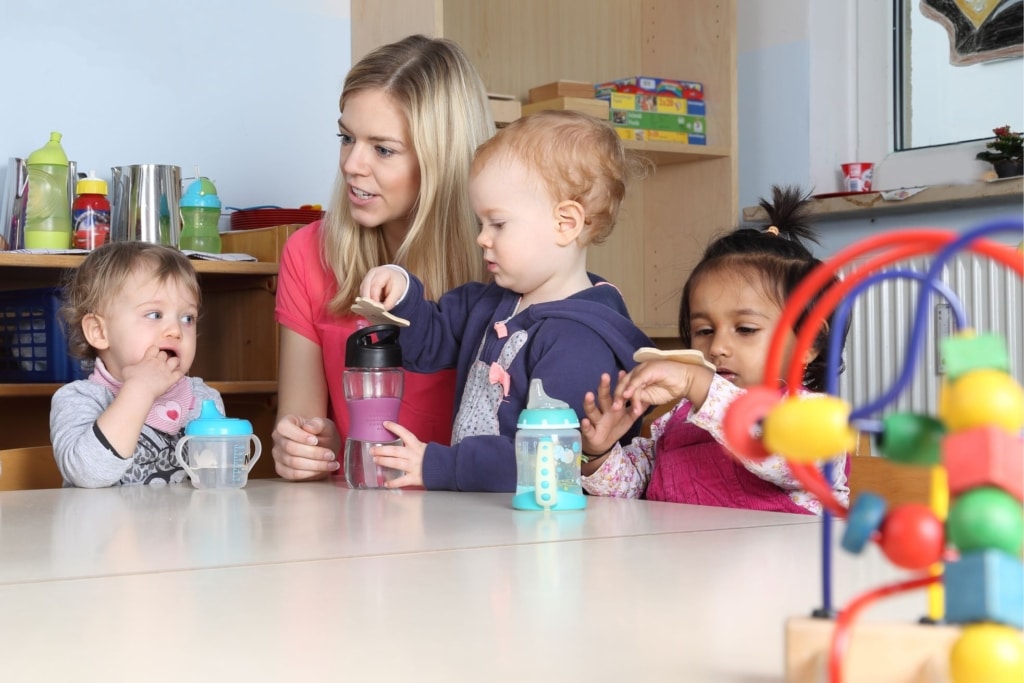 a child care provider playing with young toddlers