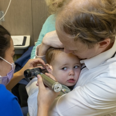 A father and toddler while the pediatrician checks his ears