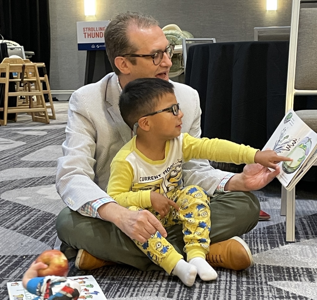 Walter Gilliam reading to child at Strolling Thunder