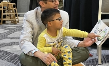 Walter Gilliam reading to child at Strolling Thunder