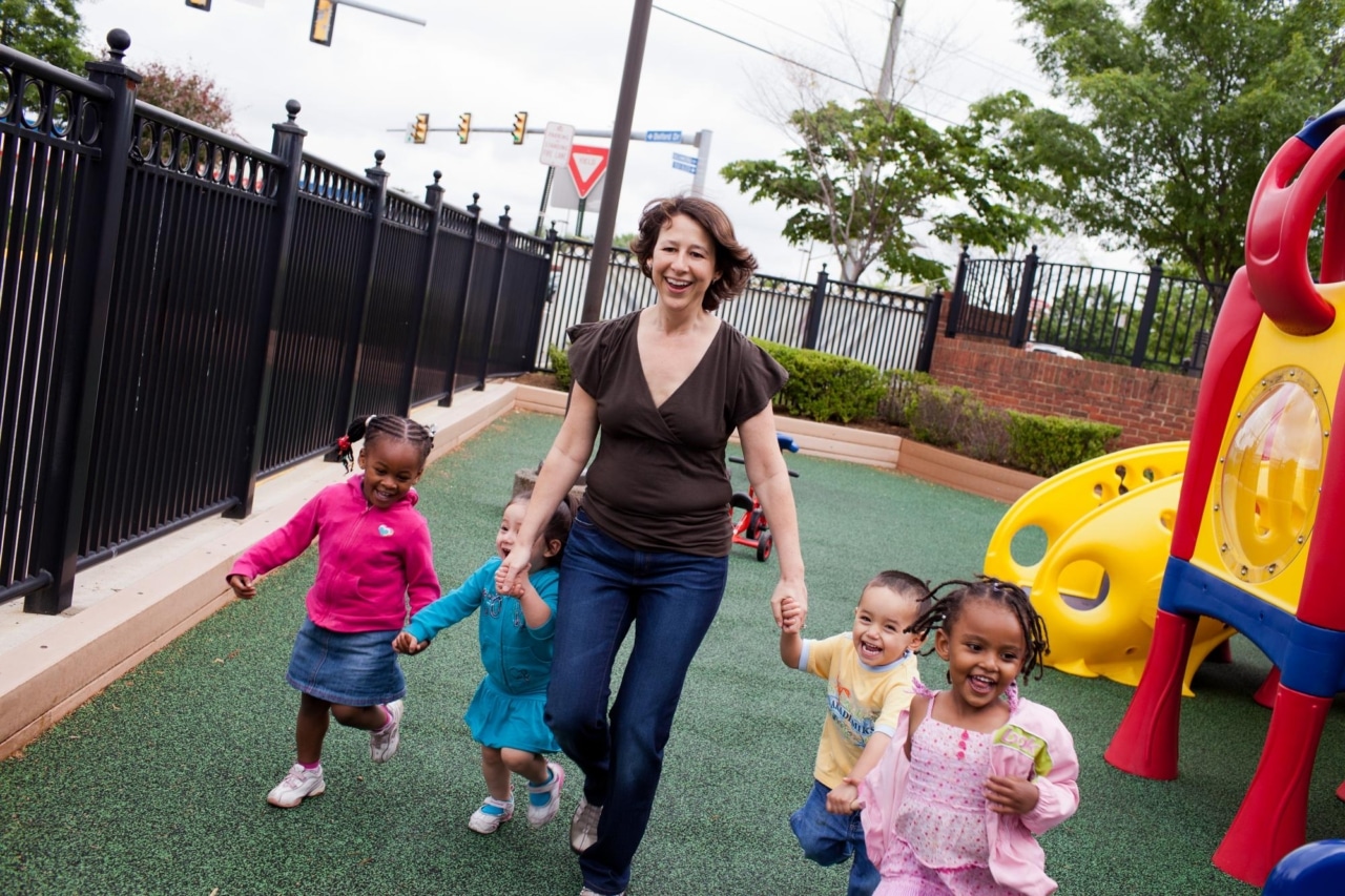 happy toddlers holding hands with an early childhood educator