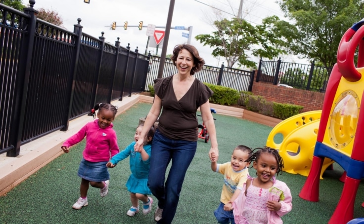 happy toddlers holding hands with an early childhood educator