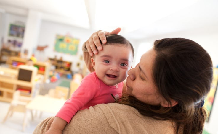 A child care worker comforts an infant