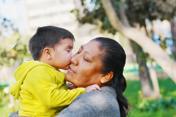 mother holds child giving kiss